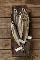 Salted air-dried sabrefish with labels on tails on wooden serving plate photo