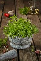 Fresh small-leaved basil in mortar with condiments on wooden table photo