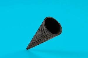 Empty, crunchy black wafer cone for ice cream on blue background. Concept of food, treats. Mockup, template for your advertising and design. Close up photo