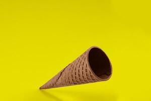 Empty wafer cone for ice cream against yellow background. Concept of food, treats. Mockup, template for your advertising and design. Close up photo