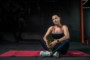 Smiling sporty girl resting after workout at gym photo