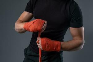 Man wrapping hands with red tape, preparing for boxing photo