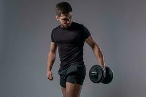 Young athletic man during weight training with dumbbells photo