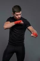 Sportsman with boxing bandages on hands working out defensive techniques photo