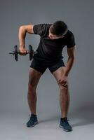 Athletic young man performing shoulder workout with dumbbells photo