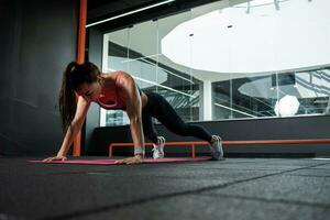 atlético mujer ejecutando Lagartijas durante formación a gimnasio foto