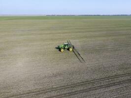 Tractor with hinged system of spraying pesticides. Fertilizing w photo