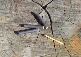 Three firecrackers and match lying on a tree stump photo