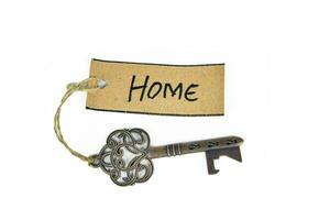 Old decorative key and handwritten tag HOME tied with straw rope on white background photo