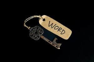 Antique old key with WORD tag on black background photo