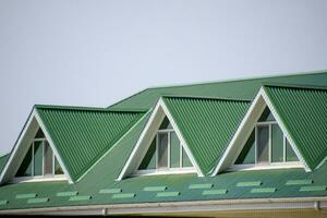 The house with plastic windows and a green roof of corrugated sh photo