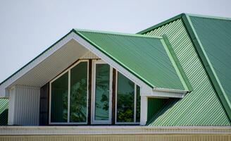 The house with plastic windows and a green roof of corrugated sh photo