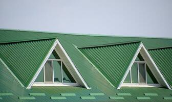 The house with plastic windows and a green roof of corrugated sh photo