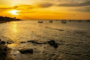 Beautiful sunset with silhouettes of people and fishing boats on the beach photo