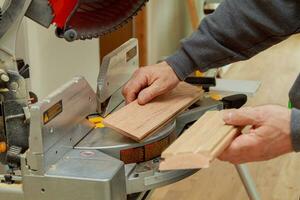 Construction worker, Trimming parquet on using circular miter saw cutting photo