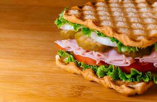 Sandwich with ham, cheese fresh vegetables on wooden cutting board photo