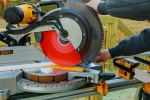 man cutting wood on electric saw photo