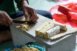 Woman's hand slicing raw tempeh on the wooden table using a knife. Tempeh or Tempe is Fermented Soy Product Originally from Indonesia photo