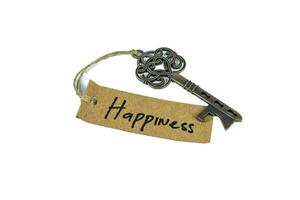 Old decorative key and handwritten tag Happiness tied with straw rope on white background photo