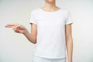 Cropped shot of young female's hand being raised while showing deaf alphabet, forming letteg h with fingers while standing over white background photo