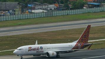 PHUKET, THAILAND - FEBRUARY 03, 2023. Airplane Boeing 737, 9M-LRD of Batik Air Malaysia taxiing at Phuket Airport, side view. Passenger flight on runway. Tourism and travel concept video