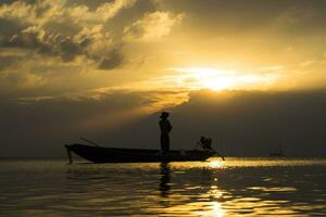 Silhouettes of fisherman at the lake with sunset, Thailand. photo