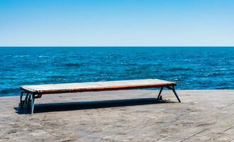 ai generado un Roca banco sentado en parte superior de un pared con vista a el Oceano foto