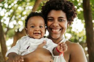 bonito contento mujer participación un recién nacido bebé en su brazos. foto