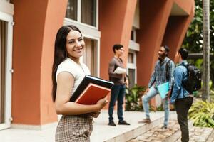 Laughing latin american female student with group of young adults. photo