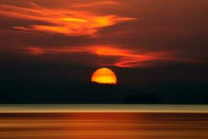 Big sun and orange cloud in sunset sky on the lake. photo