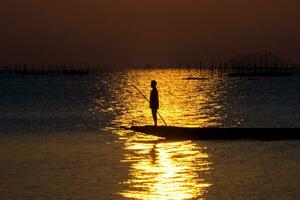 silueta pescador con puesta de sol cielo en el lago en sur de tailandia foto