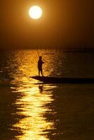 Silhouette fisherman with sunset sky on the lake in south of Thailand. photo