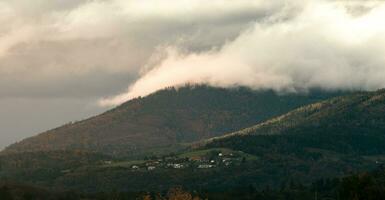 Beatiful shot of a small village on a mountain with clouds flowing over photo