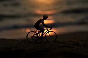siluetas ciclistas en el playa a puesta de sol. foto