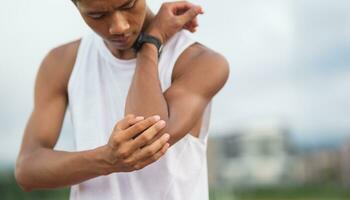 Athletes sport man runner wearing white sportswear to sitting feeling pain in his elbow after practicing on a running track at a stadium, copy space. Runner sport injury concept. photo