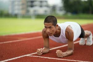 Athletes sport man runner wearing white sportswear to planking stretching and warm up before practicing on a running track at a stadium. Runner sport concept. photo