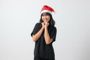 Portrait of attractive Asian woman with red Santa hat feeling happy, showing excited and cheerful expression. New year and christmas concept. Isolated image on white background photo