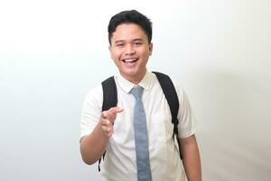 Indonesian senior high school student wearing white shirt uniform with gray tie reaching out for a handshake and greet someone. Isolated image on white background photo