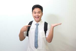 Indonesian senior high school student wearing white shirt uniform with gray tie, smiling and looking at the camera, showing something with hands. Isolated image on white background photo