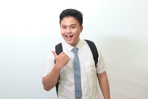 indonesio mayor alto colegio estudiante vistiendo blanco camisa uniforme con gris Corbata demostración producto, señalando a alguna cosa y sonriente. aislado imagen en blanco antecedentes foto