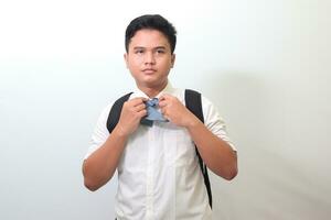 Indonesian senior high school student wearing white shirt uniform with gray tie adjusting his necktie. Isolated image on white background photo