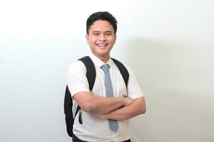 Indonesian senior high school student wearing white shirt uniform with gray tie keeping arms crossed and looking at camera. Isolated image on white background photo