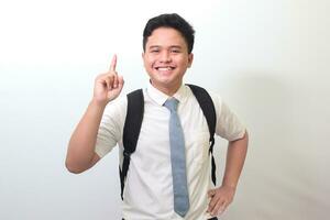 indonesio mayor alto colegio estudiante vistiendo blanco camisa uniforme con gris Corbata señalando arriba con dedo y recordando alguna cosa a hacer. aislado imagen en blanco antecedentes foto