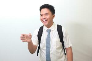 Indonesian senior high school student wearing white shirt uniform with gray tie reaching out for a handshake and greet someone. Isolated image on white background photo