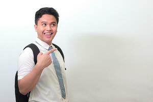 Indonesian senior high school student wearing white shirt uniform with gray tie showing product, pointing at something and smiling. Isolated image on white background photo