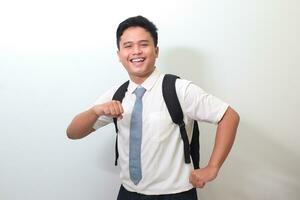 Indonesian senior high school student wearing white shirt uniform with gray tie showing making fun and dancing gesture with hands. Isolated image on white background photo