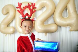 Merry Christmas 2024 concept Boy receives a gift from his mother at christmas photo