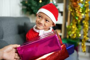 Merry Christmas 2024 concept Boy receives a gift from his mother at christmas photo