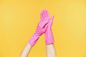 Studio photo of raised two hands touching each other while applying soap on it before washing it, isolated over orange background. Human hands concept