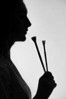 Profile silhouette of a girl holding brushes. photo